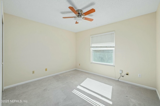 empty room with a textured ceiling, light carpet, a ceiling fan, and baseboards