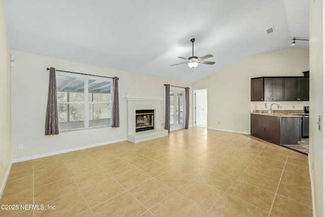 unfurnished living room with visible vents, lofted ceiling, ceiling fan, a fireplace, and light tile patterned flooring