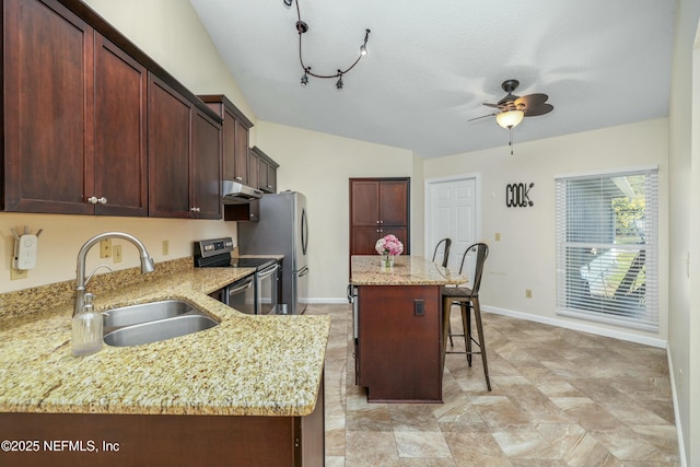 kitchen featuring a kitchen island, a breakfast bar, stainless steel appliances, under cabinet range hood, and a sink