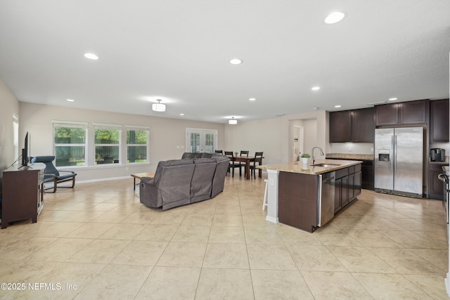 kitchen featuring dark brown cabinetry, open floor plan, recessed lighting, a sink, and appliances with stainless steel finishes