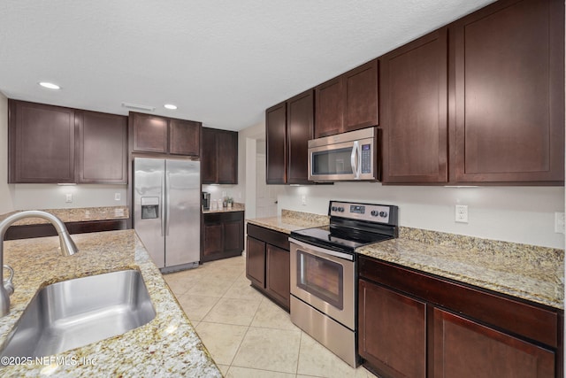 kitchen with light stone countertops, recessed lighting, a sink, appliances with stainless steel finishes, and light tile patterned floors