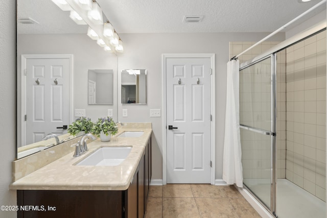 bathroom featuring visible vents, a tile shower, and a sink
