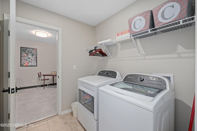 clothes washing area featuring laundry area, baseboards, washing machine and dryer, and light tile patterned flooring