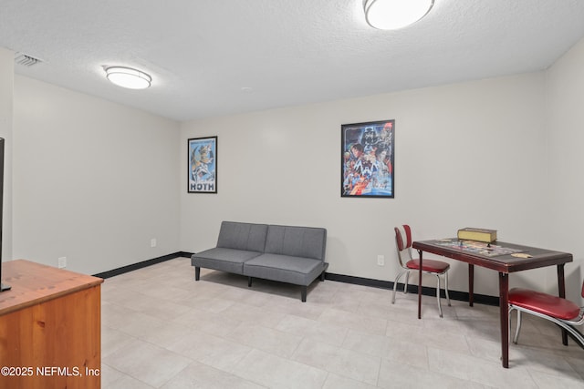 living area featuring baseboards, a textured ceiling, and visible vents