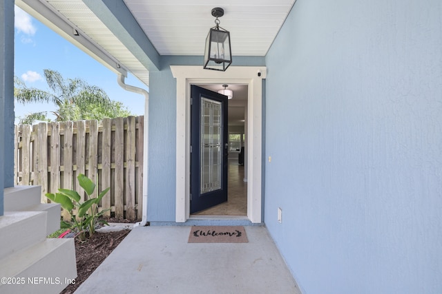 doorway to property with fence and stucco siding