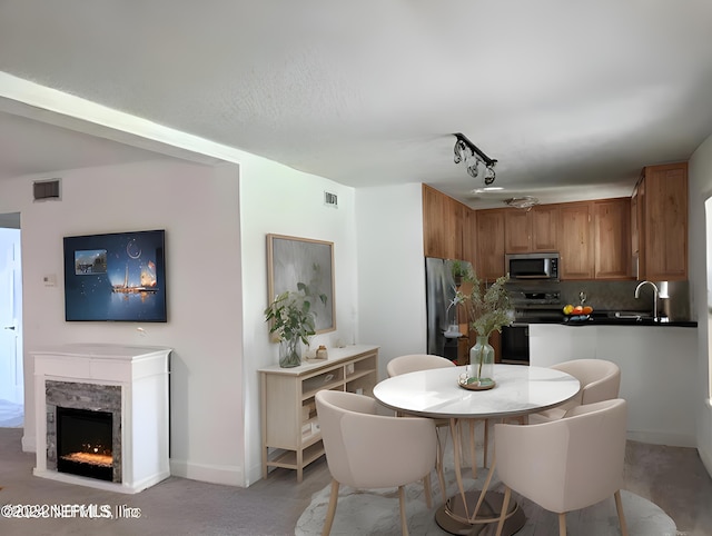 dining room with track lighting, a fireplace, visible vents, and baseboards