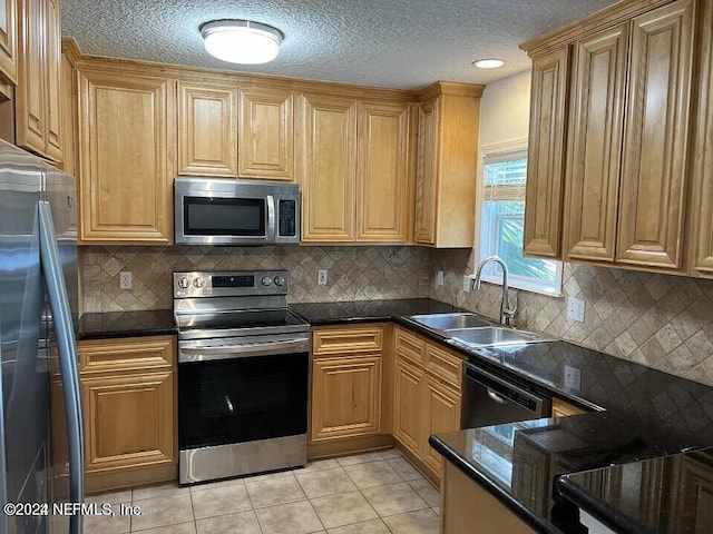 kitchen with stainless steel appliances, light tile patterned flooring, a sink, and backsplash