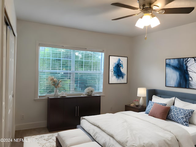 bedroom featuring a ceiling fan, a closet, baseboards, and wood finished floors