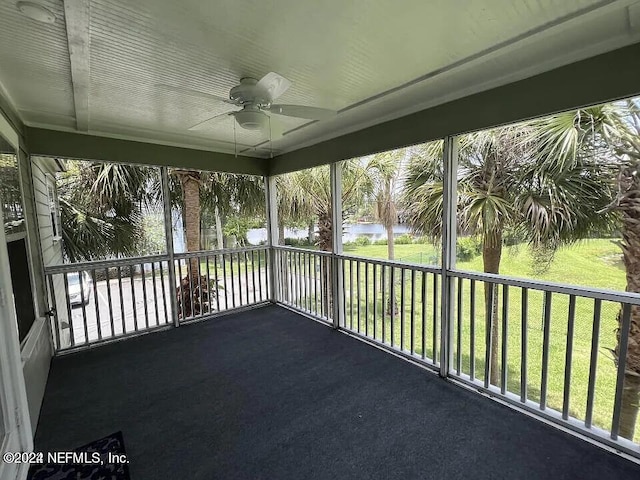 unfurnished sunroom with a water view, a ceiling fan, and a wealth of natural light