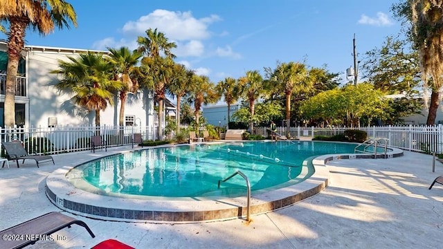 community pool with a patio area and fence