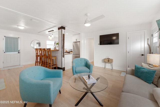 living room with a healthy amount of sunlight, light wood-style flooring, and a ceiling fan