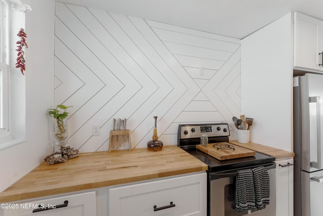 kitchen with butcher block countertops, white cabinetry, and appliances with stainless steel finishes