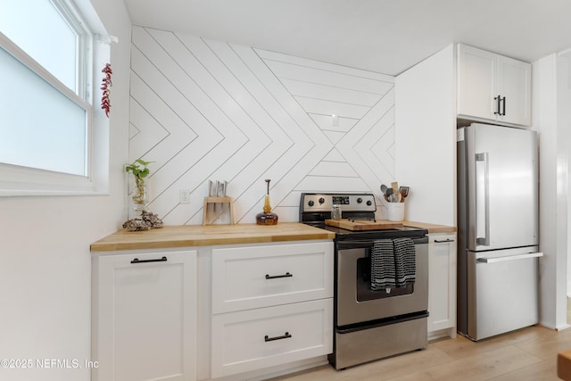 kitchen featuring white cabinets, butcher block counters, stainless steel appliances, and light wood-style flooring