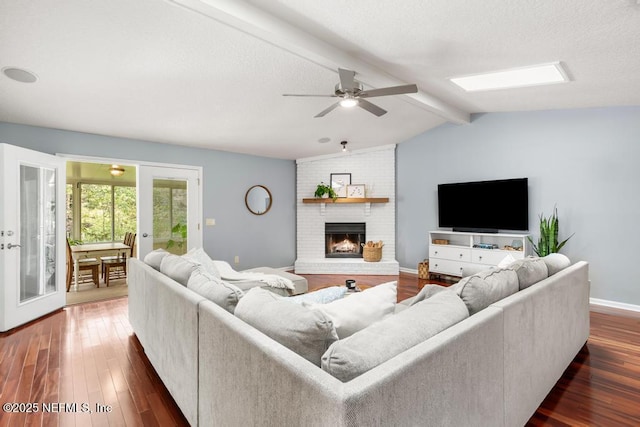 living room with lofted ceiling with skylight, a textured ceiling, a brick fireplace, and dark wood-style floors