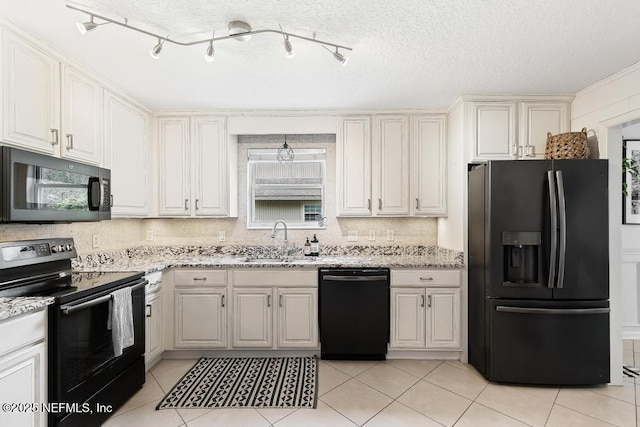 kitchen featuring light stone countertops, light tile patterned floors, decorative backsplash, black appliances, and a sink