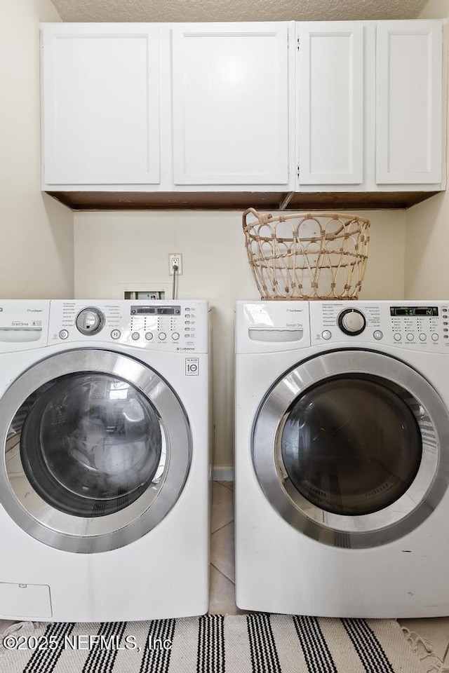 laundry room featuring tile patterned floors, washing machine and dryer, and cabinet space