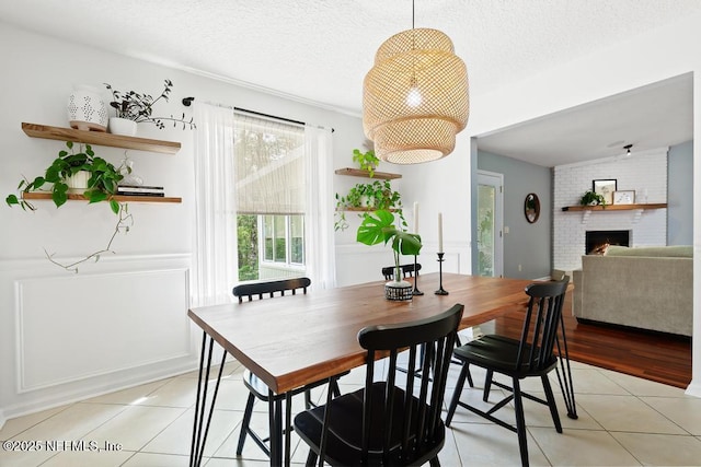 dining area with light tile patterned floors, a fireplace, and a textured ceiling