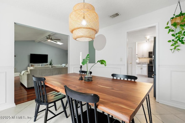 dining area featuring a decorative wall, light tile patterned floors, a ceiling fan, and visible vents