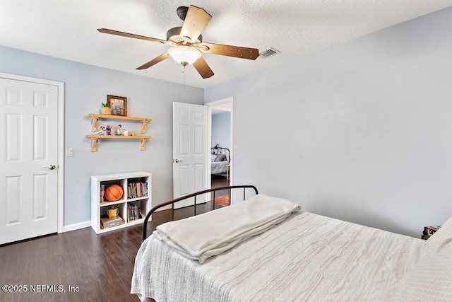 bedroom featuring visible vents, a textured ceiling, wood finished floors, baseboards, and ceiling fan