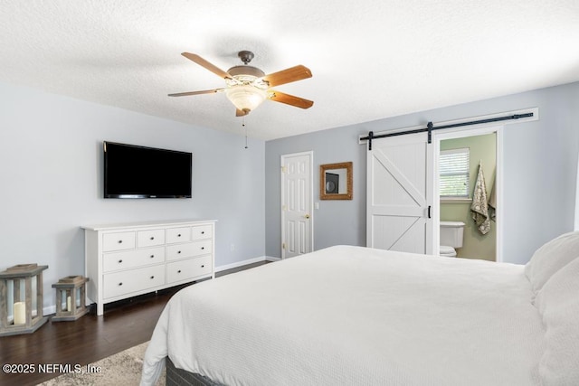 bedroom featuring a ceiling fan, a textured ceiling, dark wood finished floors, a barn door, and baseboards