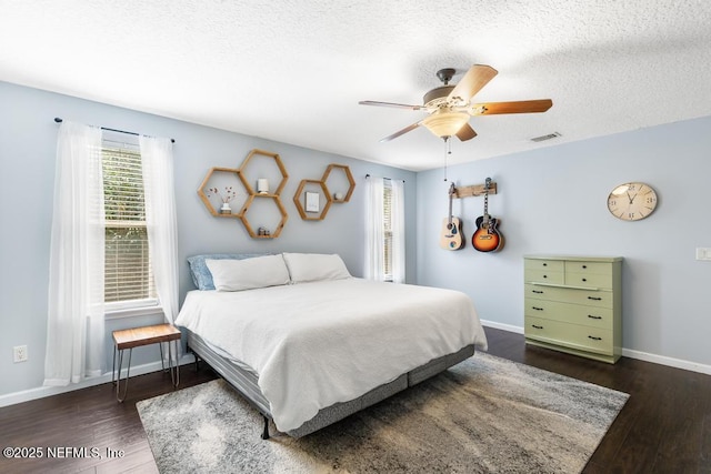 bedroom featuring wood finished floors, visible vents, baseboards, ceiling fan, and a textured ceiling