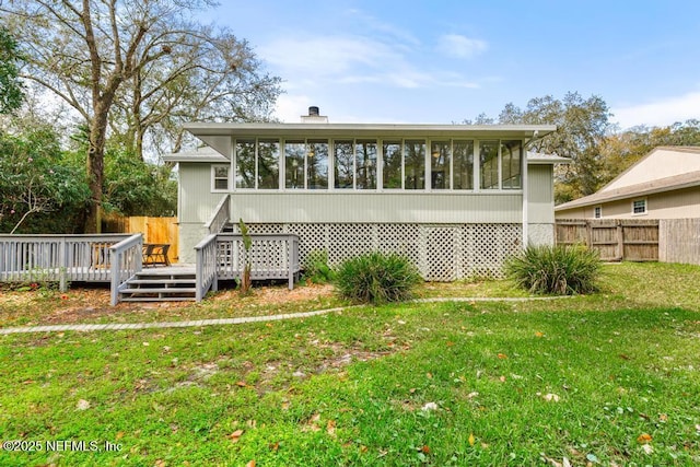 rear view of property featuring a yard, fence, a deck, and a sunroom