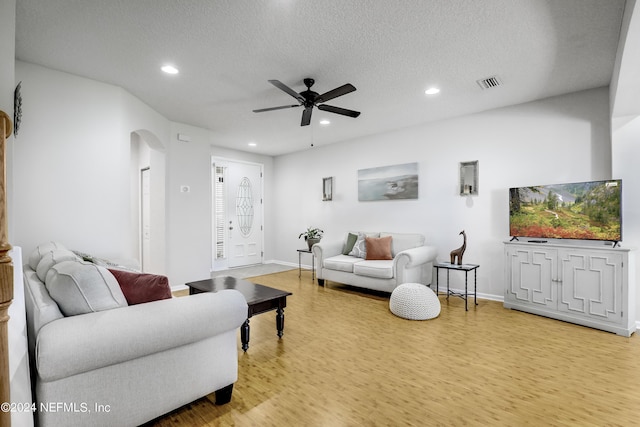 living area with arched walkways, a textured ceiling, recessed lighting, visible vents, and light wood-style floors