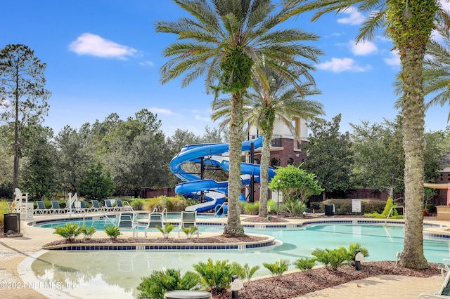 community pool featuring a water slide and fence