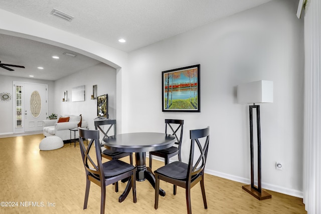 dining space featuring light wood-style floors, arched walkways, visible vents, and a ceiling fan