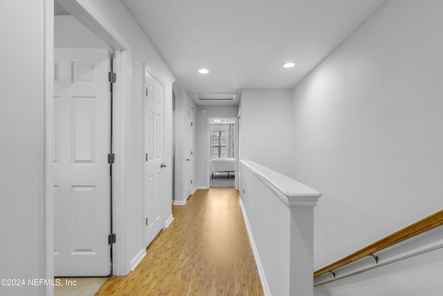 corridor with light wood finished floors, attic access, baseboards, an upstairs landing, and recessed lighting