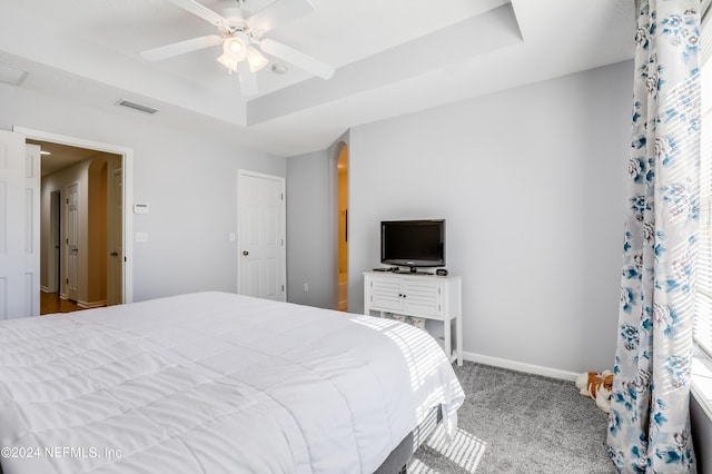 bedroom with arched walkways, carpet flooring, visible vents, baseboards, and a tray ceiling