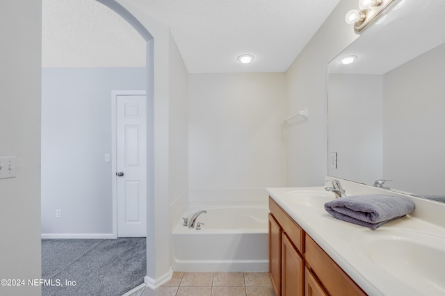 full bathroom with double vanity, a sink, a textured ceiling, tile patterned flooring, and a bath