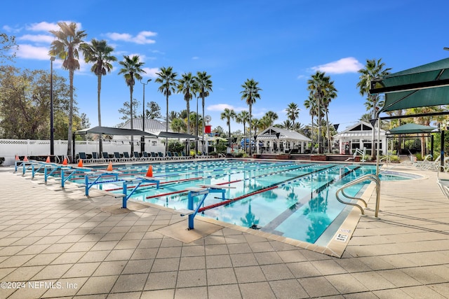 community pool with a patio area, fence, and a gazebo