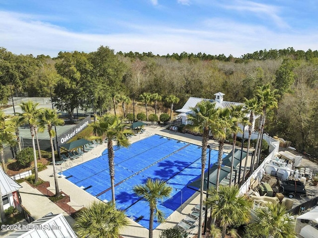 view of swimming pool featuring a patio, a view of trees, and fence