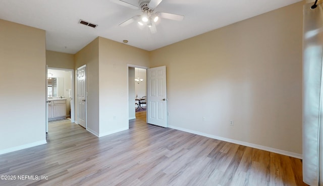 unfurnished bedroom featuring light wood finished floors, connected bathroom, visible vents, and baseboards