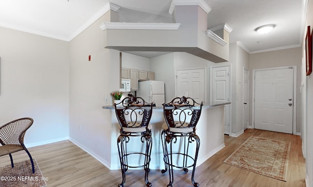 kitchen featuring white appliances, ornamental molding, and light wood finished floors