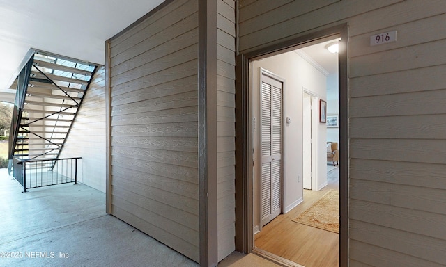 corridor featuring wood walls, wood finished floors, and crown molding