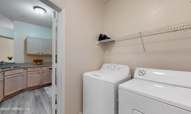 laundry area featuring laundry area, a sink, light wood-style flooring, and washer and dryer