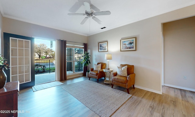 sitting room featuring ceiling fan, crown molding, baseboards, and wood finished floors