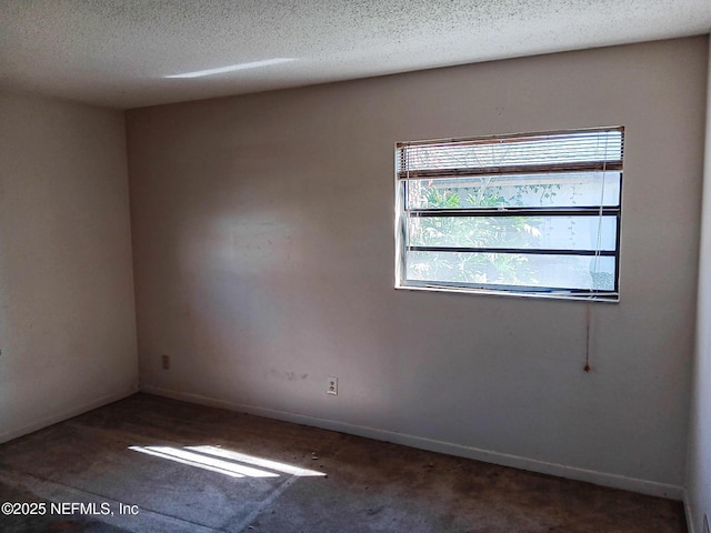 spare room featuring a textured ceiling and baseboards