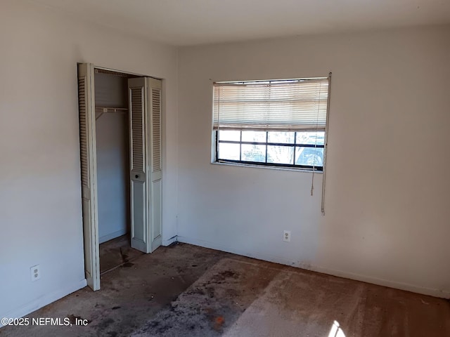 unfurnished bedroom featuring unfinished concrete floors, baseboards, and a closet