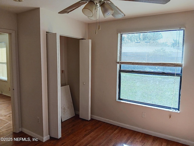 unfurnished bedroom featuring multiple windows, wood finished floors, and baseboards