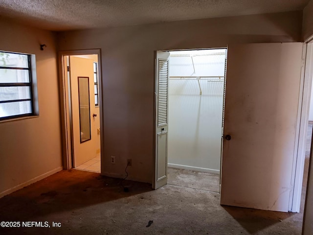 unfurnished bedroom with a closet, ensuite bathroom, and a textured ceiling