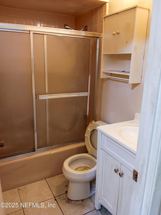 bathroom featuring enclosed tub / shower combo, toilet, vanity, and tile patterned flooring