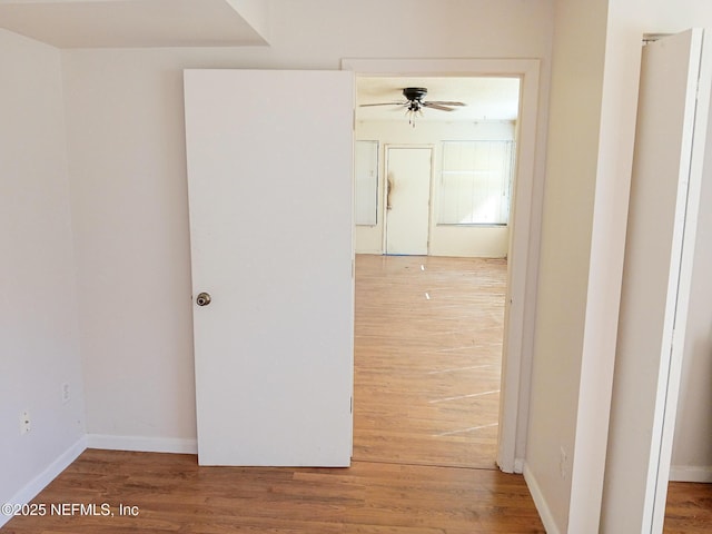 hall with baseboards and wood finished floors