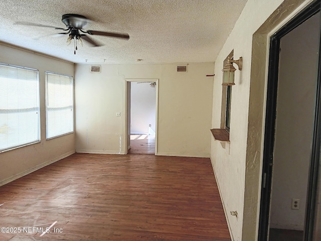 unfurnished room with visible vents, a textured ceiling, wood finished floors, and a ceiling fan