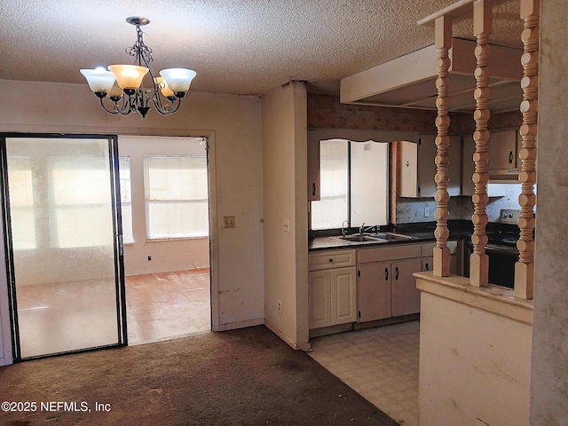 kitchen featuring a textured ceiling, hanging light fixtures, black range with electric cooktop, and a sink