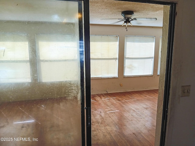 interior space with a textured ceiling, wood finished floors, and a ceiling fan