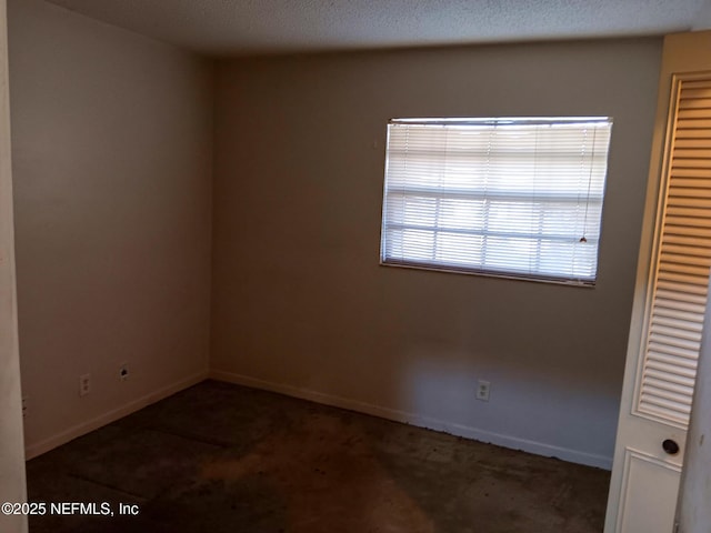 carpeted empty room with baseboards and a textured ceiling