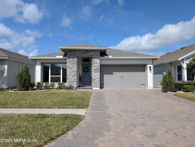 view of front of property with stone siding, a garage, decorative driveway, and a front lawn